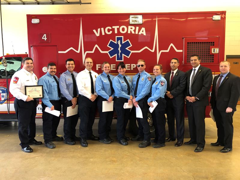 Group photo of several people, some in firefighter dress shirts, in front of an ambulance.