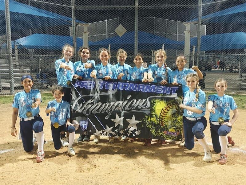 Preteen softball team holding a championship banner and showing their championship rings