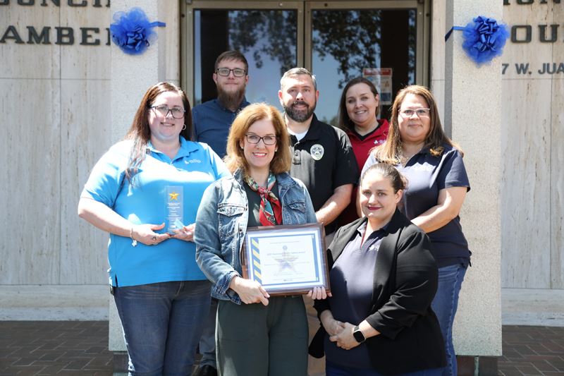 Group photo with framed certificate in front of Municipal Court building