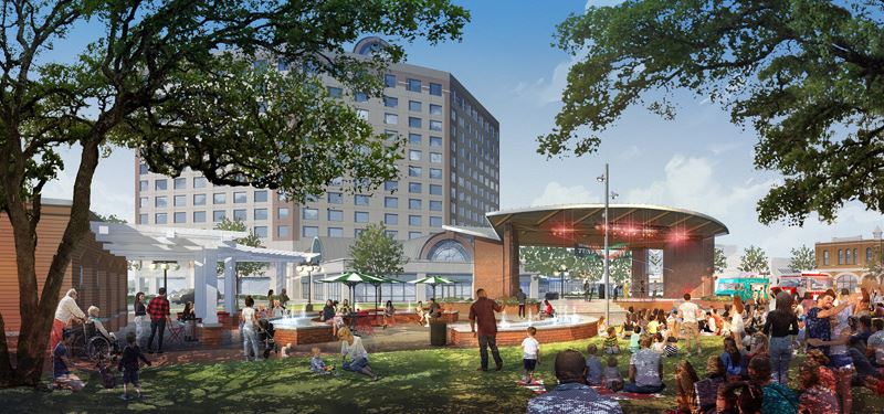 A large permanent stage at DeLeon Plaza near the O'Connor building. People watch and mill around.