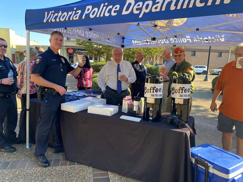 Officer John Turner, Gary Moses and others gather around an outdoor table with coffee and breakfast