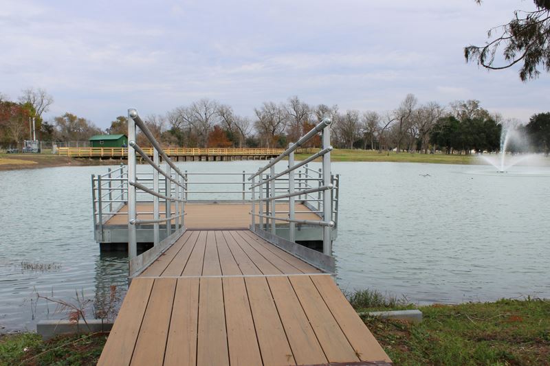 Floating fishing pier at the duck pond. Boardwalk and decorative fountain in background