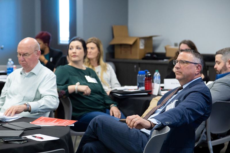 People sitting around tables listening to someone off-camera