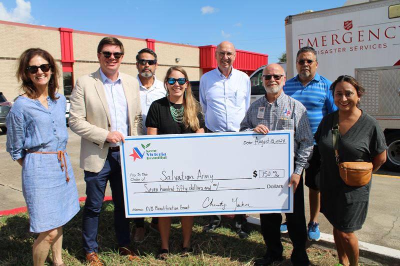 Group photo with giant check in front of Salvation Army building