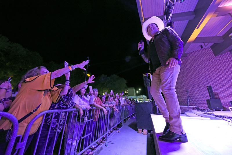 A singer in a cowboy hat and a black leather jacket performs at the De Leon Plaza pavilion