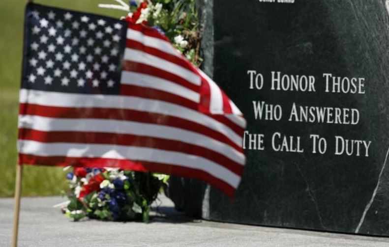 American flag in front of a memorial that states 