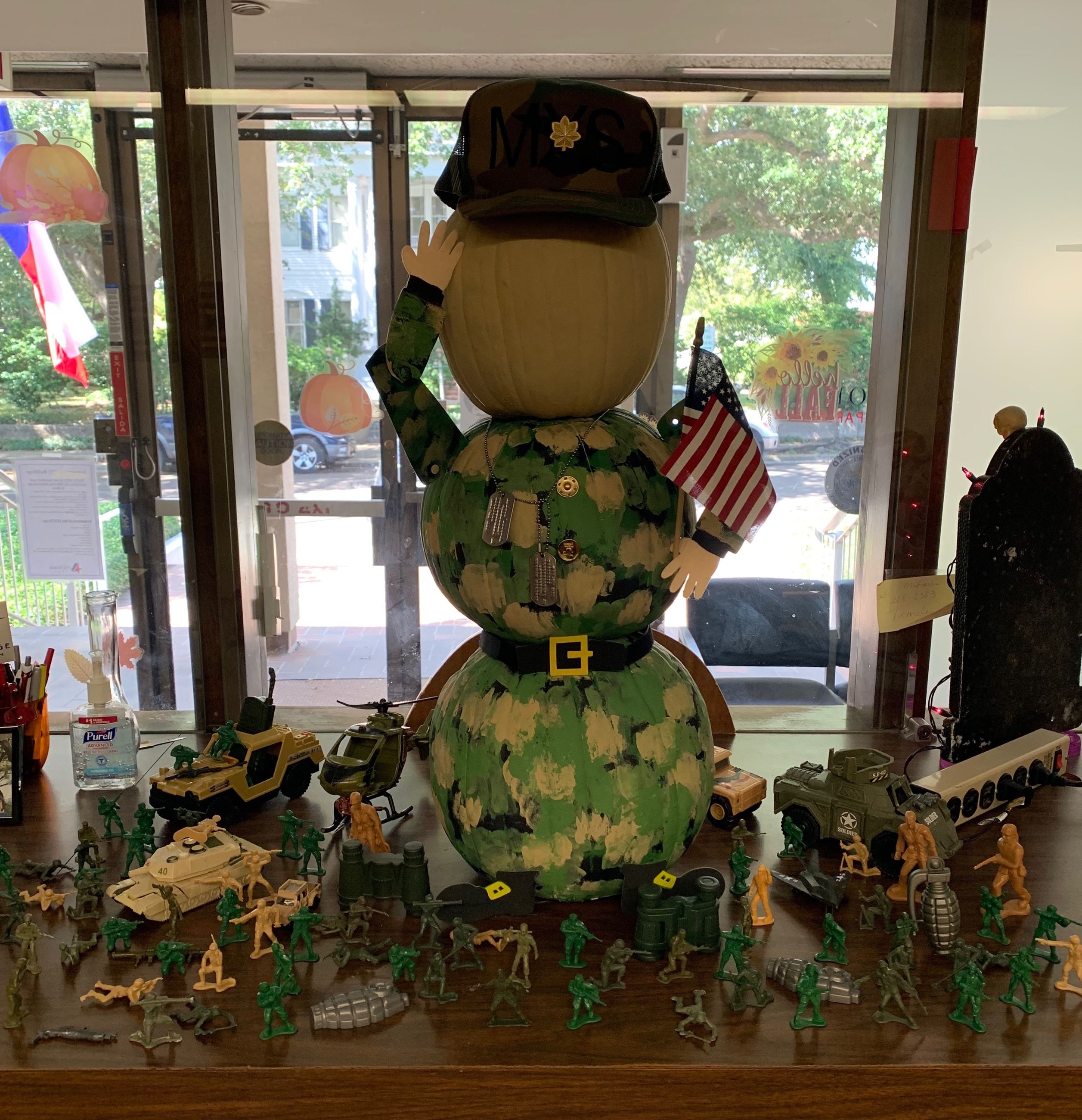 Camo-clad figure made of three stacked pumpkins. Surrounded by toy soldiers