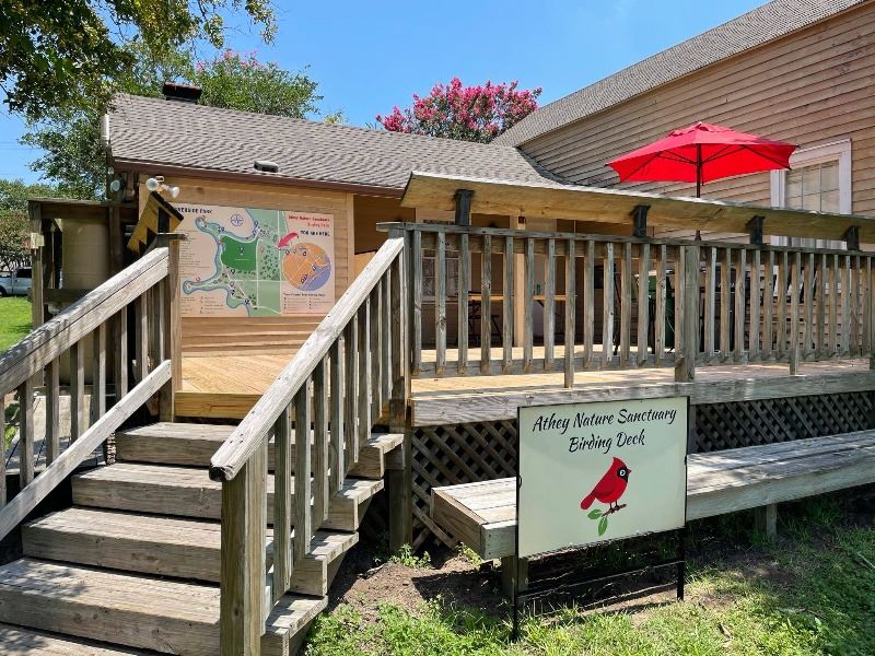 An elevated wooden patio with a shaded seating area, a map of Riverside Park and additional signage.
