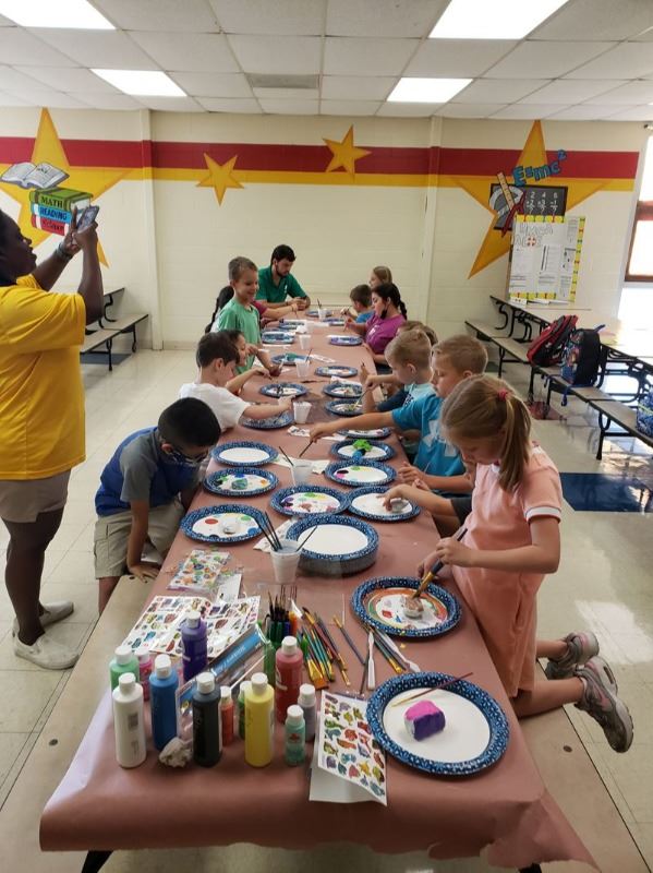 Kids at school lunch table painting rocks