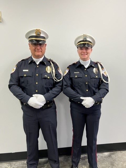 Two uniformed police officers wearing white hats and white gloves