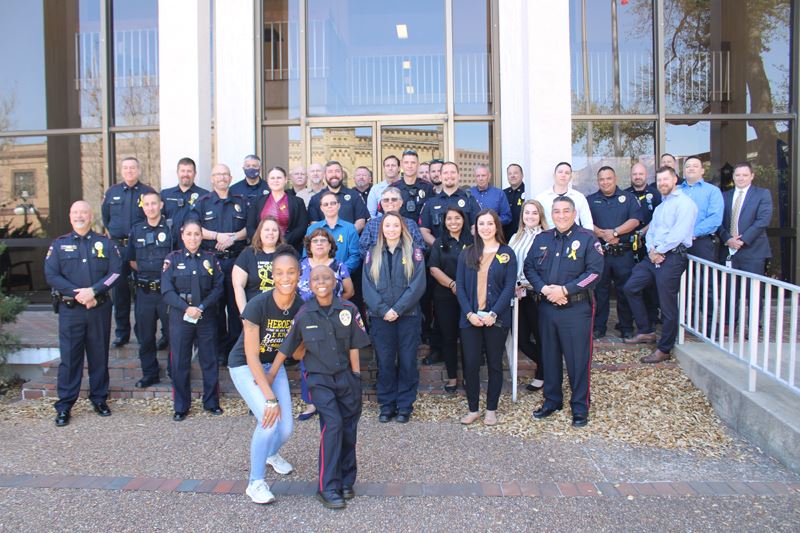 A young girl and a woman with multiple uniformed officers in the background outside at City Hall