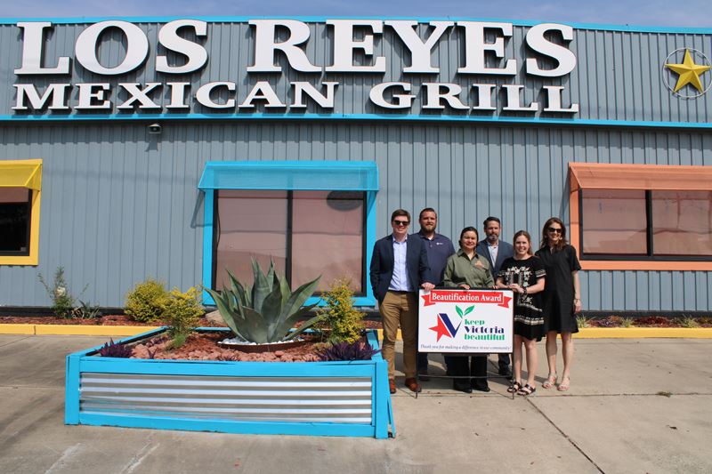 Group photo with KVB sign in front of Los Reyes Mexican Grill next to flowerbed with succulents.