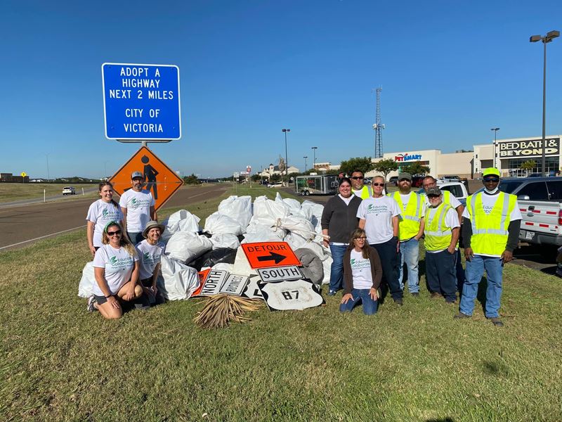 People in Keep Victoria Beautiful shirts pose with trash bags on the Loop