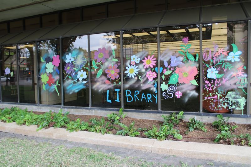 A wide window painted with flowers and the word Library