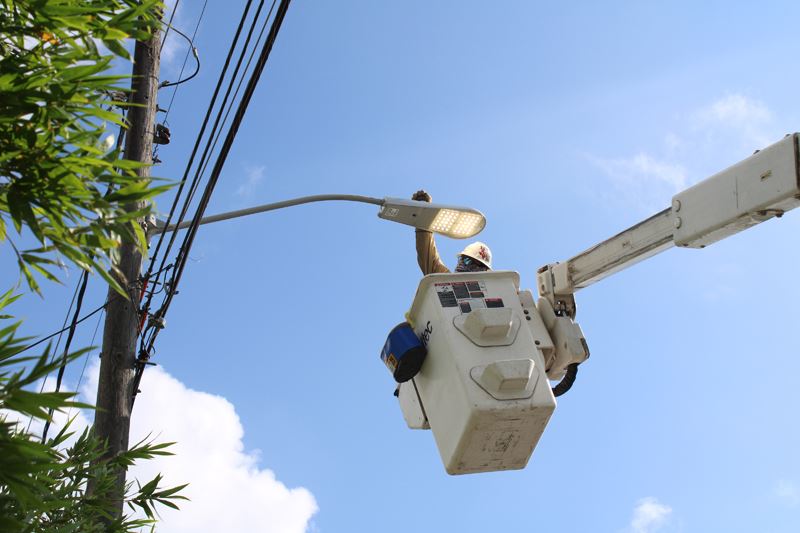 Man in cherry picker installs an overhead LED street light.