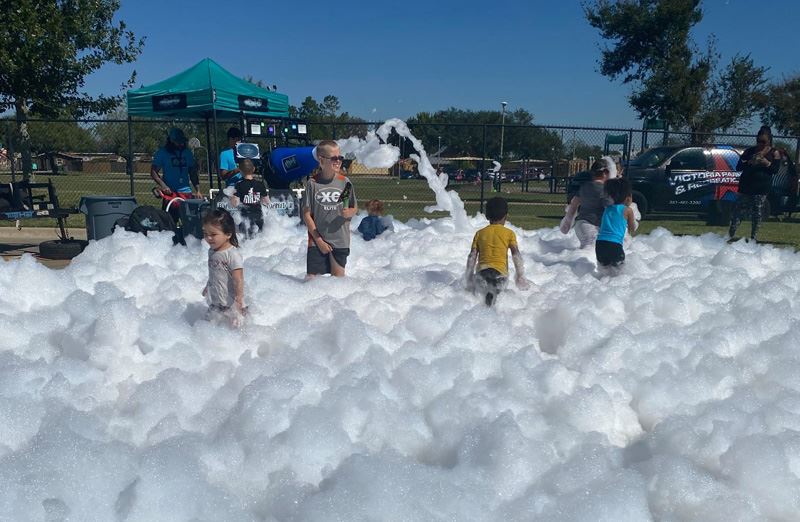 Kids play in foam bubbles in a parking lot