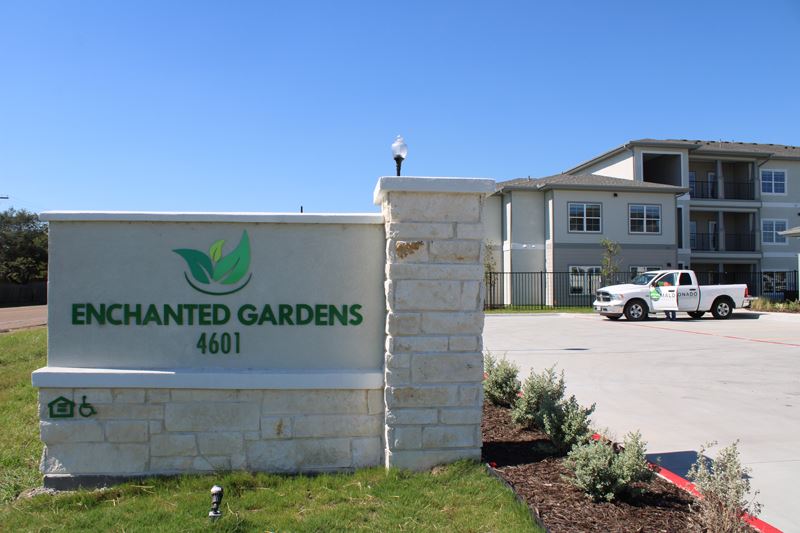 Sign in front of an apartment says Enchanted Gardens 4601