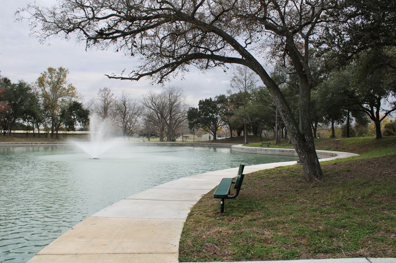 Duck pond surrounded by a winding concrete path with a concrete retaining wall below