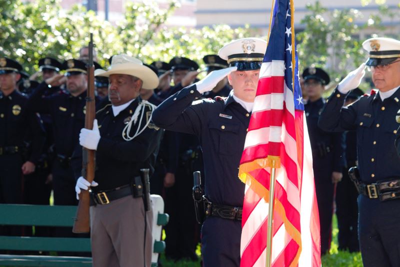 Police officers salute an American flag