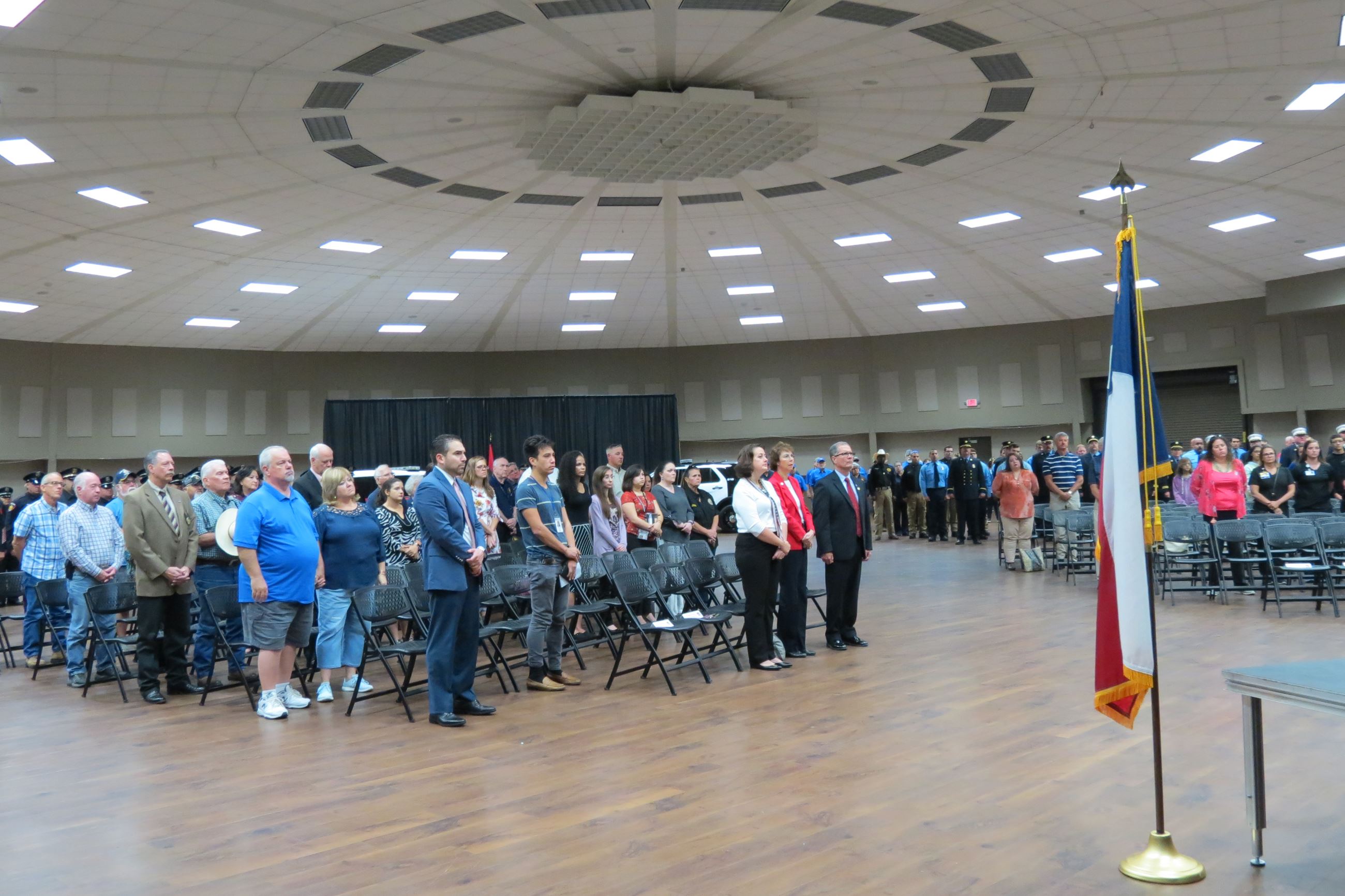 Audience members stand during a ceremony at the Victoria Community Center