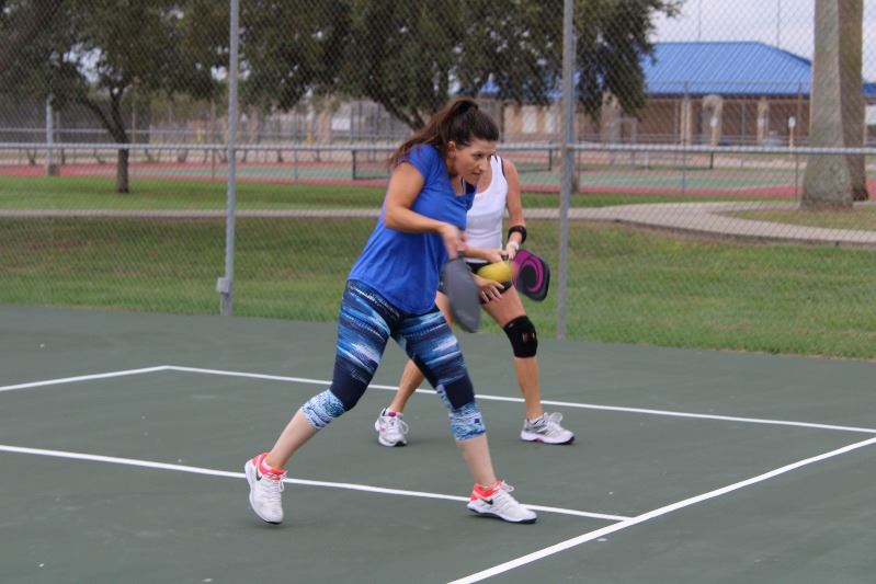 Woman playing pickleball hits the ball.