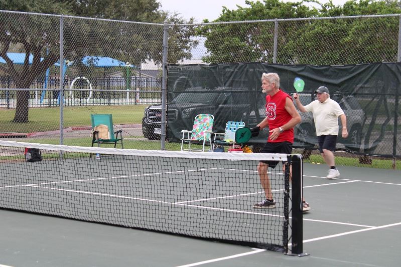 Two men stand on one side of the court during a game of pickleball.