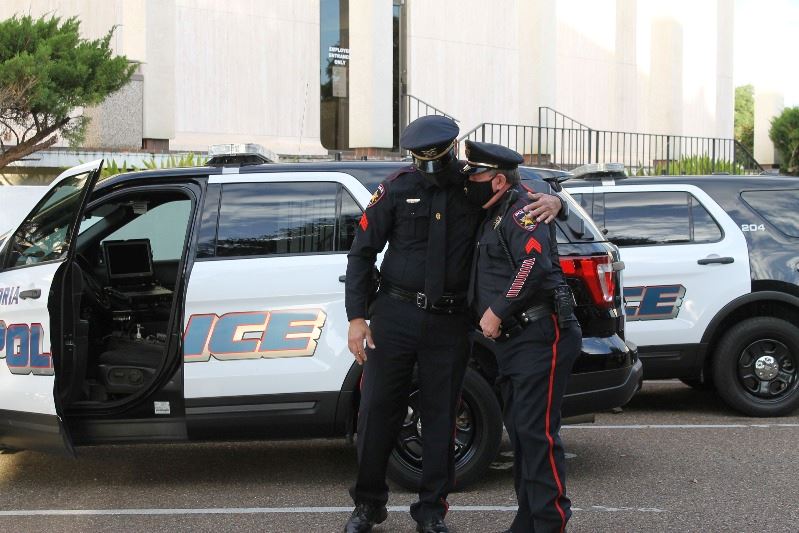Two masked police officers stand near squad car in parking lot
