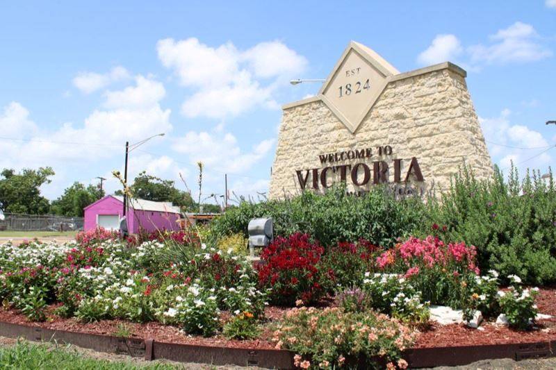 Welcome to Victoria sign with large, colorful flowerbed in front