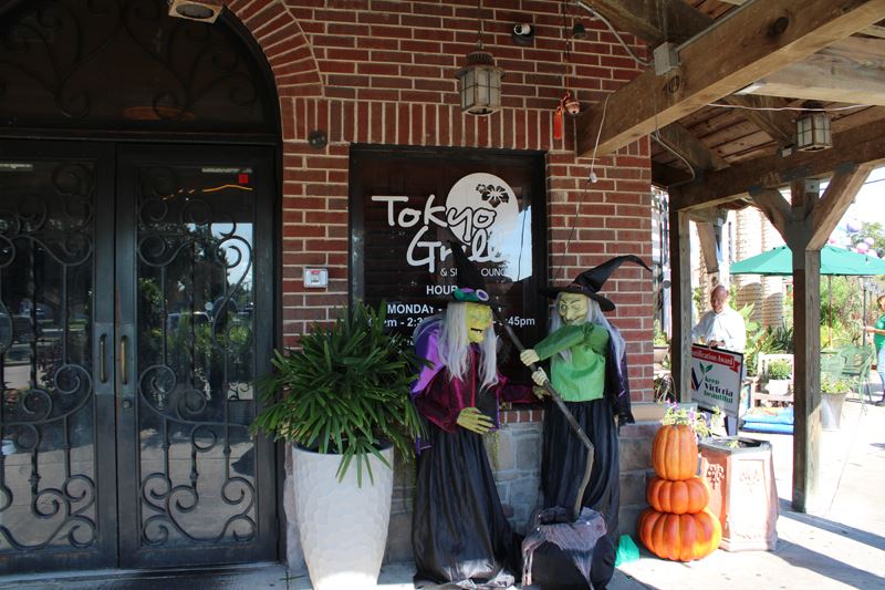 Decorative Halloween witches and pumpkins sit at the front door to Tokyo Grill.