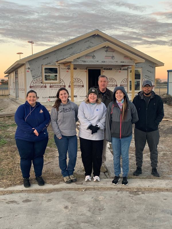 Group photo in front of an unfinished home