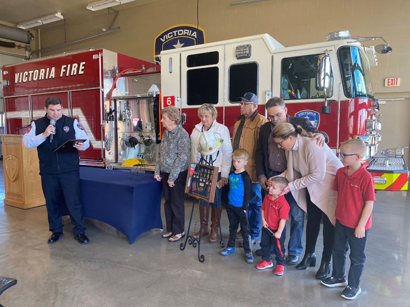 Man reads from a plaque near a group of 8 people of different ages.