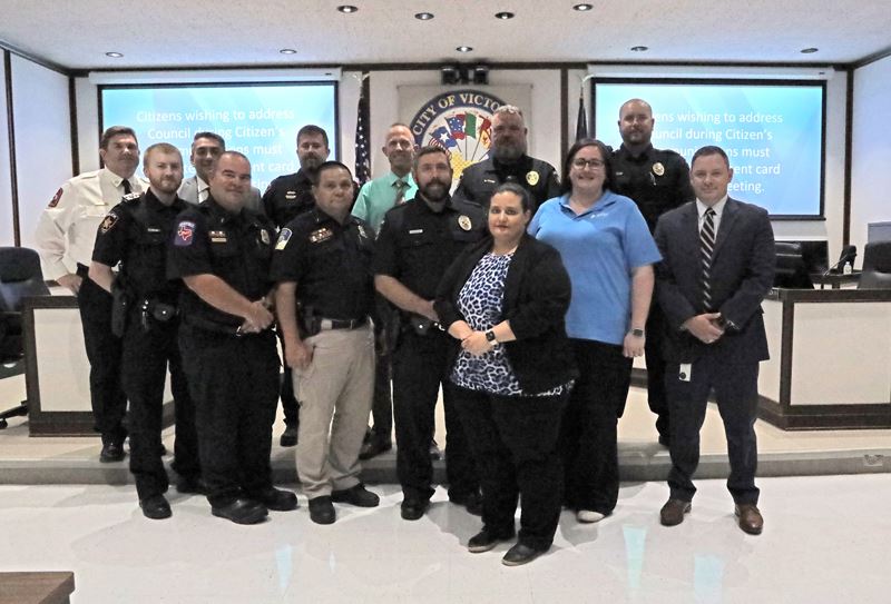 Group photo of people, some in fire or police uniform, at Council chambers