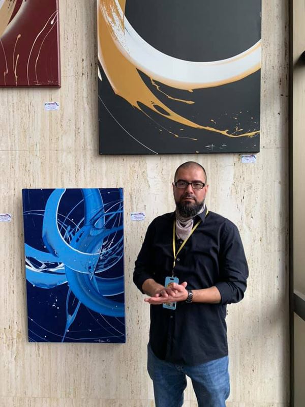 A man poses with colorful abstract art with sweeping designs.